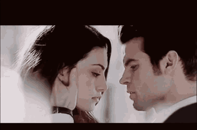 a man and a woman are looking into each other 's eyes and touching their faces .