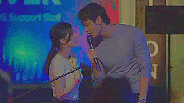 a man is holding a microphone next to a woman who is singing into it .