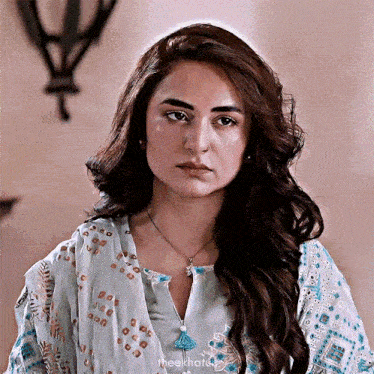 a woman with a nose ring is wearing a blue and white dress and necklace