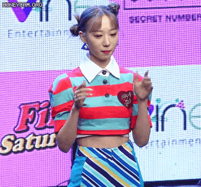 a woman in a striped shirt stands in front of a sign that says secret number entertainment