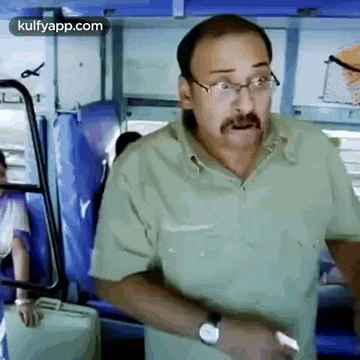 a man wearing glasses and a mustache is standing on a train .