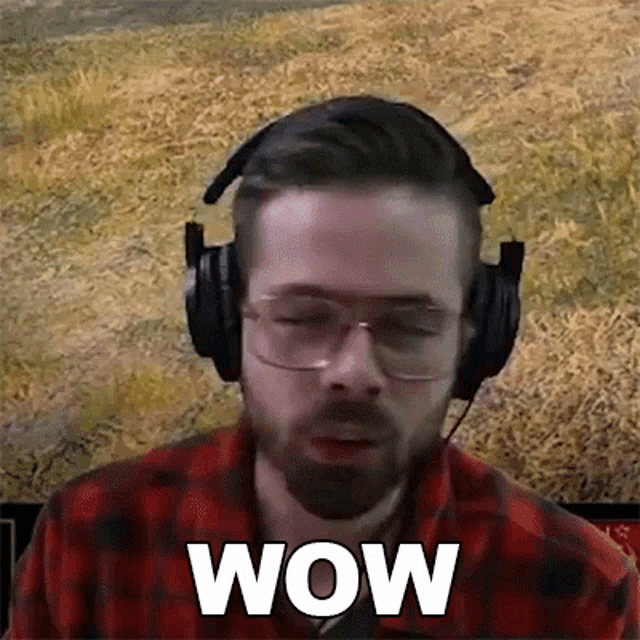a man with a beard is wearing headphones and glasses and says wow .