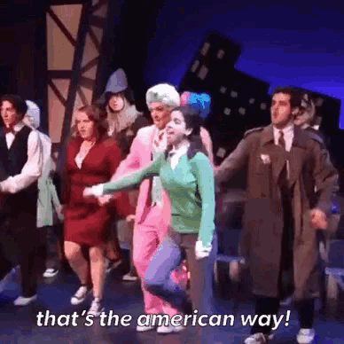 a group of people are dancing on a stage with the words that 's the american way written on the bottom .