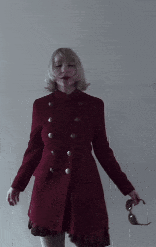 a woman in a red coat is holding a pair of glasses