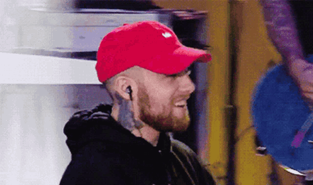 a man with a beard wearing a red hat and headphones