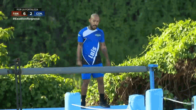 a man in a blue shirt that says luis is standing in front of a fence