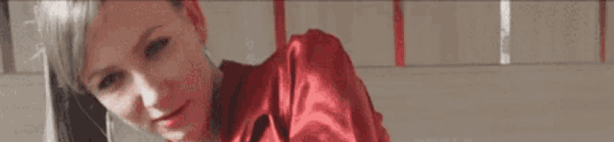 a woman wearing a red satin shirt is looking down