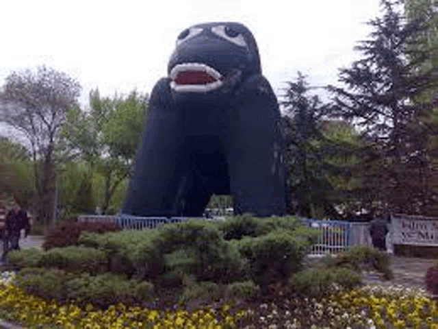 a large inflatable gorilla statue is in a park surrounded by trees and flowers .