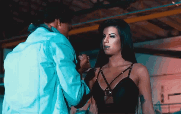 a woman in a black top is being photographed by a man in a blue jacket