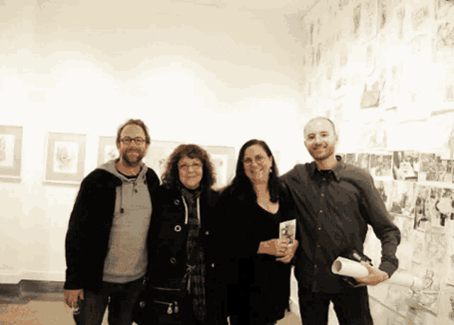 a group of people posing for a photo in front of a wall of pictures