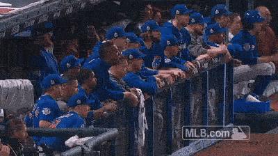 a group of baseball players are running on a field with a mlb.com sign in the background .