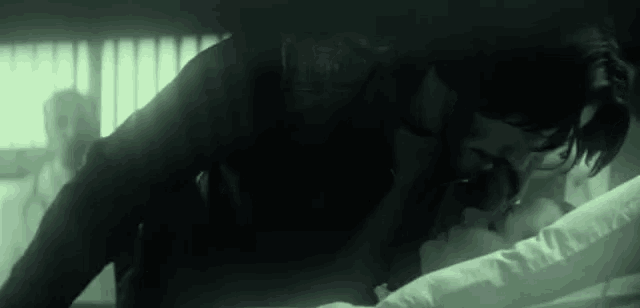 a man is kissing a woman on the forehead while laying on a bed .