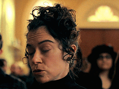 a close up of a woman 's face with her eyes closed and her hair in a bun