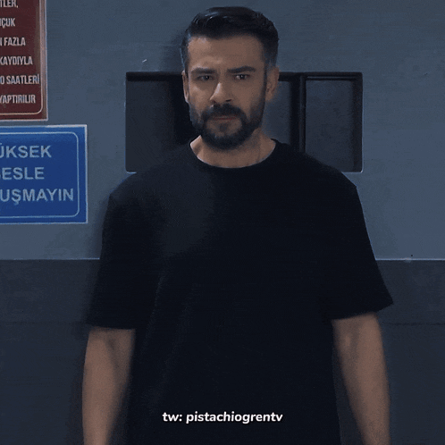 a man in a black shirt is standing in front of a sign that says ayin on it