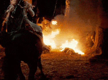 a person riding a horse with a fire in the background