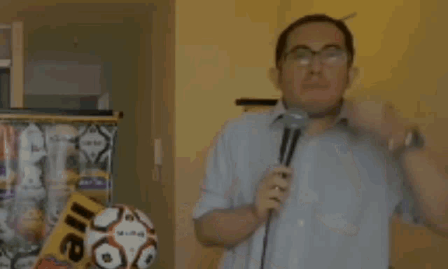 a man is holding a soccer ball in front of a microphone .