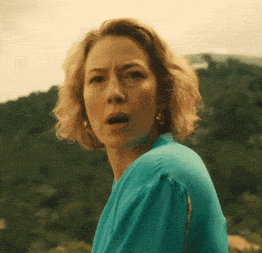 a woman with a surprised look on her face is wearing a blue top