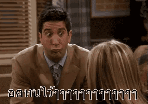a man in a suit and tie is making a funny face while talking to a woman in a room .