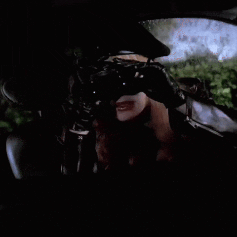 a woman wearing sunglasses and a hat holds binoculars