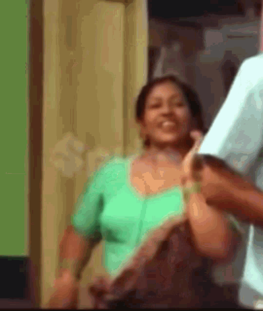 a woman in a green top is smiling while standing next to a man in a blue shirt .