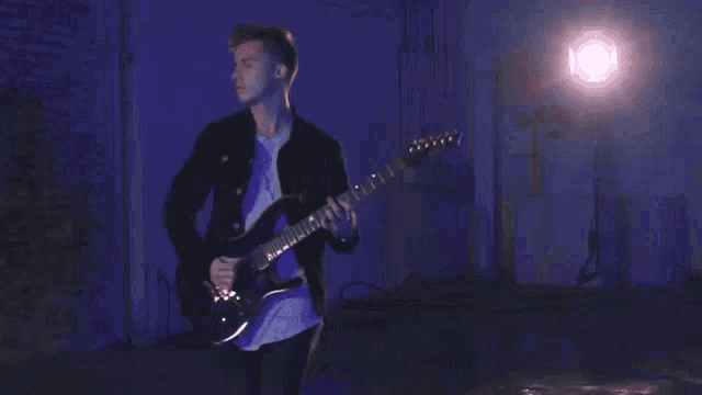 a man is playing a guitar in a dark room .