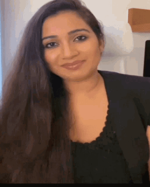 a woman with long hair is wearing a black top and a black jacket .