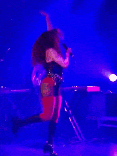 a woman is dancing on a stage with a microphone