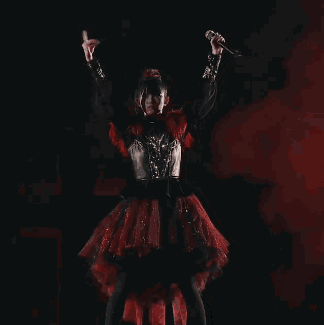 a girl in a red and black dress is giving a rock on sign