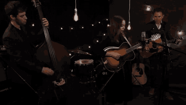 a man playing a double bass a woman playing a guitar and a man playing a guitar in a band