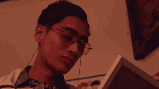 a man wearing glasses looks at a framed picture