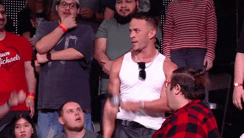 a man in a white tank top is standing in front of a crowd wearing a red shirt that says dawn michaels