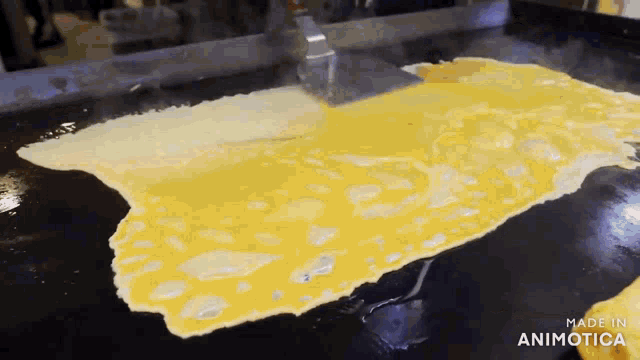 a large piece of omelet is being cooked on a grill with the words made in animotica visible in the corner