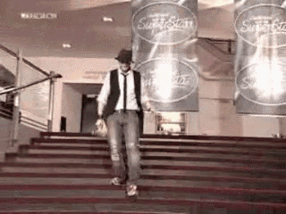 a man is walking down a set of stairs in front of a sign that says superstar .