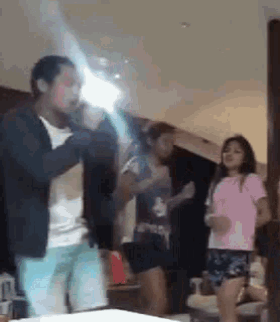 a group of people are dancing in a room while a man is holding a light saber .