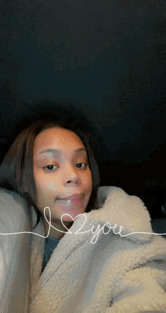 a woman sitting in a car with the words i 2 you written on her face