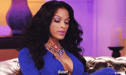 a woman in a blue dress is sitting on a couch and says hater !