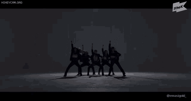 a group of people are standing in a row with their arms in the air