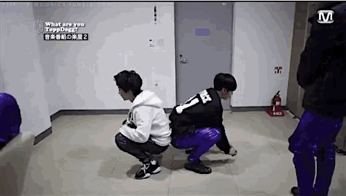 a group of young men squatting down in a hallway with a fire extinguisher in the background