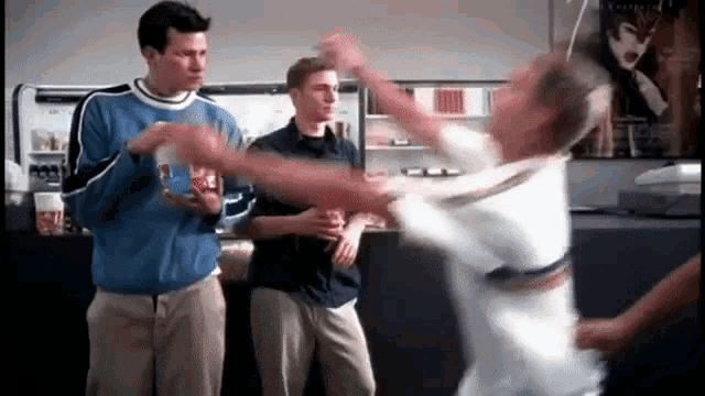 a group of men are standing in a room eating popcorn and dancing .