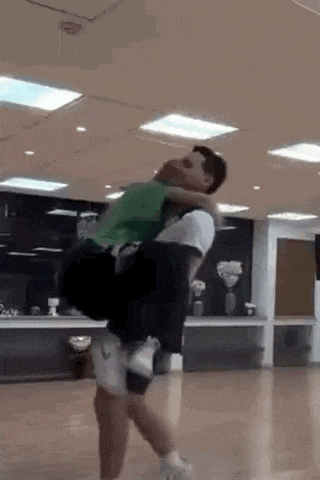 a man is carrying another man on his back in a dance studio .