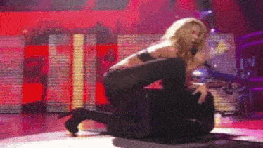 a woman is kneeling on a man on a stage .