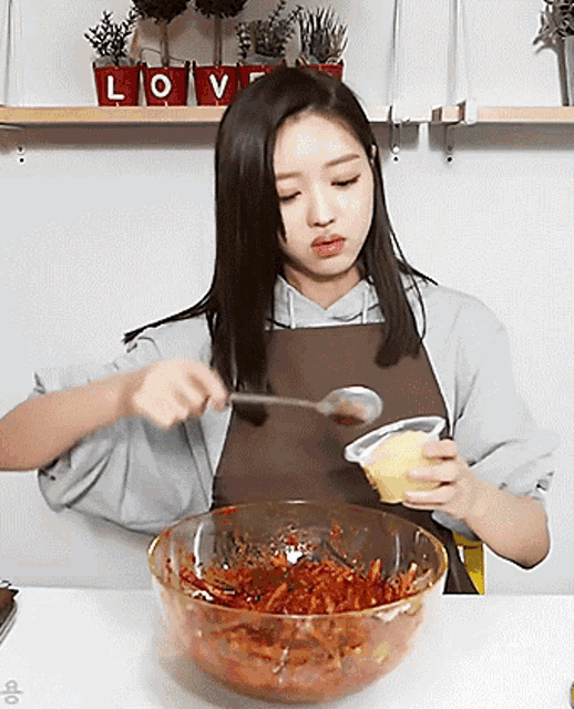 a woman in an apron is mixing a bowl of food with a spoon