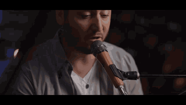 a man singing into a microphone with a purple background