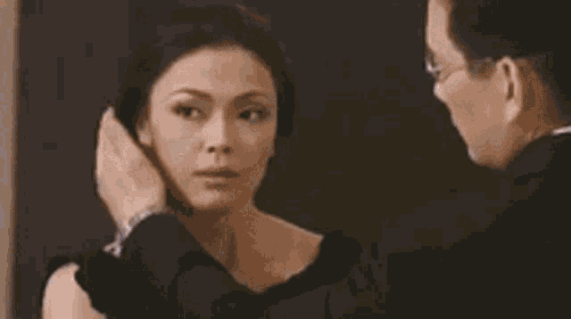 a man in a suit and glasses is talking to a woman in a restaurant .