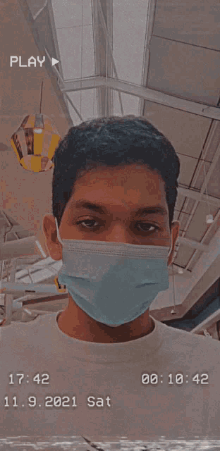 a man wearing a face mask has a play button on the bottom right