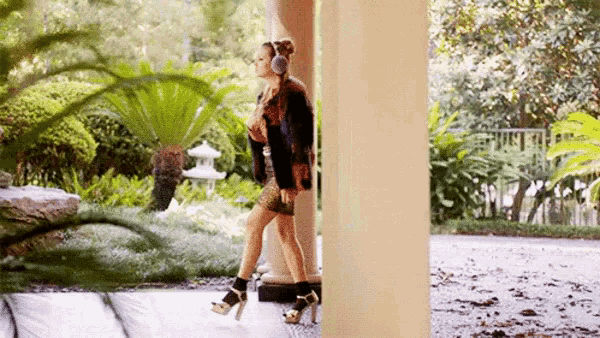 a woman is walking between two pillars on a porch .