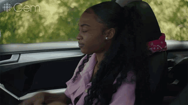 a woman is sitting in the driver 's seat of a car with the word gem on the bottom left