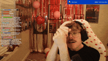 a man wearing headphones is sitting in front of a red curtain with balloons and a sign that says blood hunter