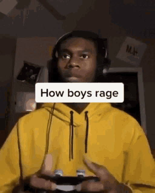 a man wearing headphones and a yellow hoodie is holding a game controller .