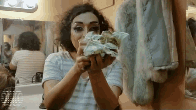 a woman holding a pile of money in front of a mirror
